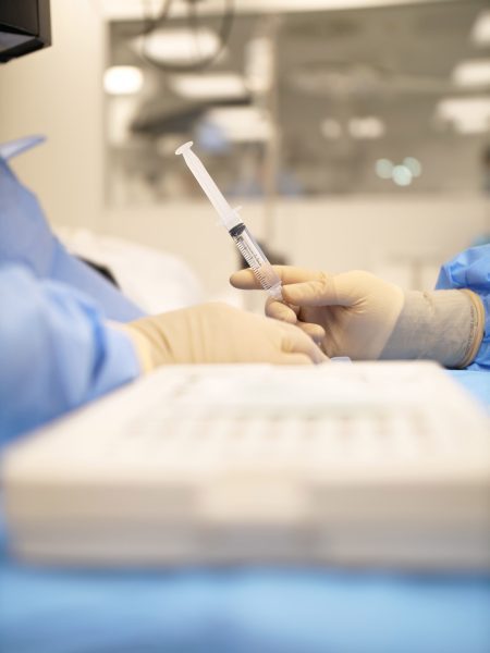 Profesionales del ICQO sujetan una jeringuilla durante la realización de un ensayo clínico